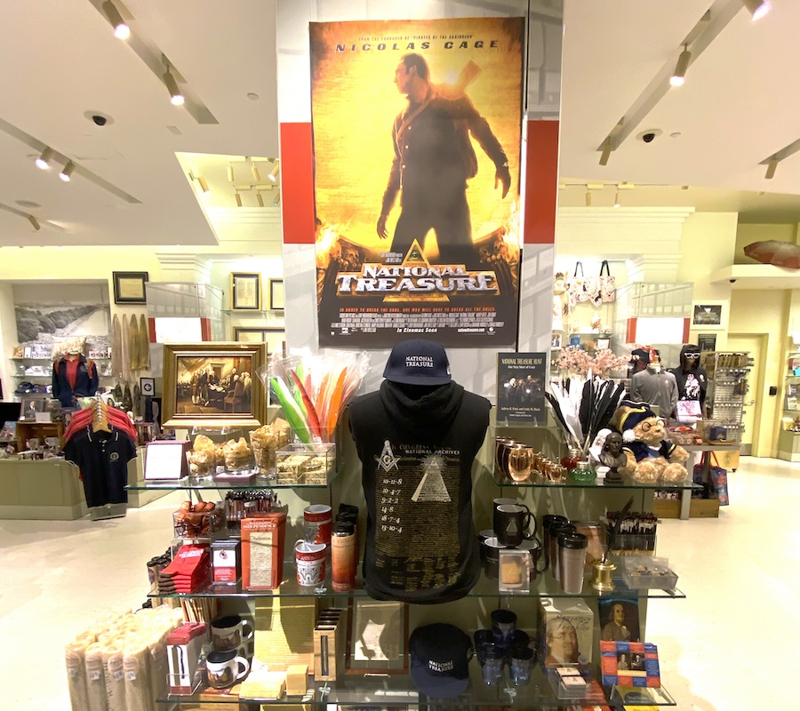 A display in the National Archives gift shop showcases memorabilia from National Treasure, including a poster of Nicolas Cage and themed merchandise.