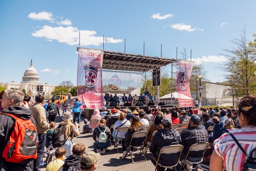 A street festival with a big stage and pink decorations on Pennsylvania Avenue in front of the U.S. Capitol. 
