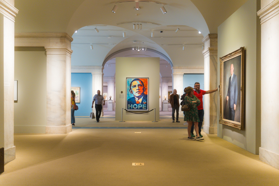 Visitors explore a hallway of presidential portraits at the National Portrait Gallery, with Shepard Fairey’s iconic “HOPE” portrait of Barack Obama prominently displayed.