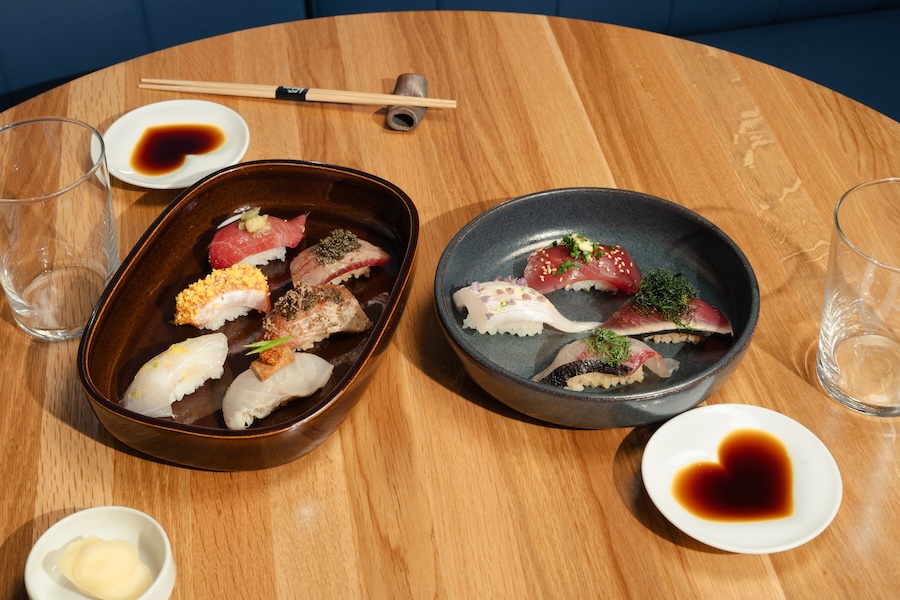 Assorted sushi dishes with dipping sauce and chopsticks at Love, Makoto.