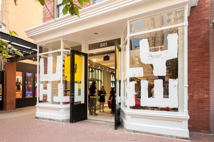 The entrance to Woolly Mammoth Theatre Company in downtown Washington, DC, with open doors and people gathering inside beneath bold window graphics.