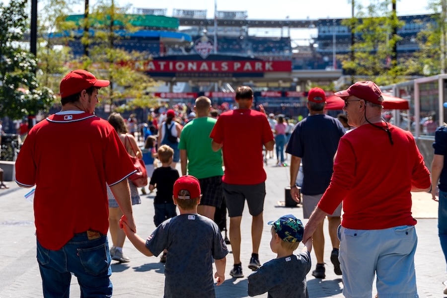Families in red jerseys walking toward Nationals Park for a baseball game.