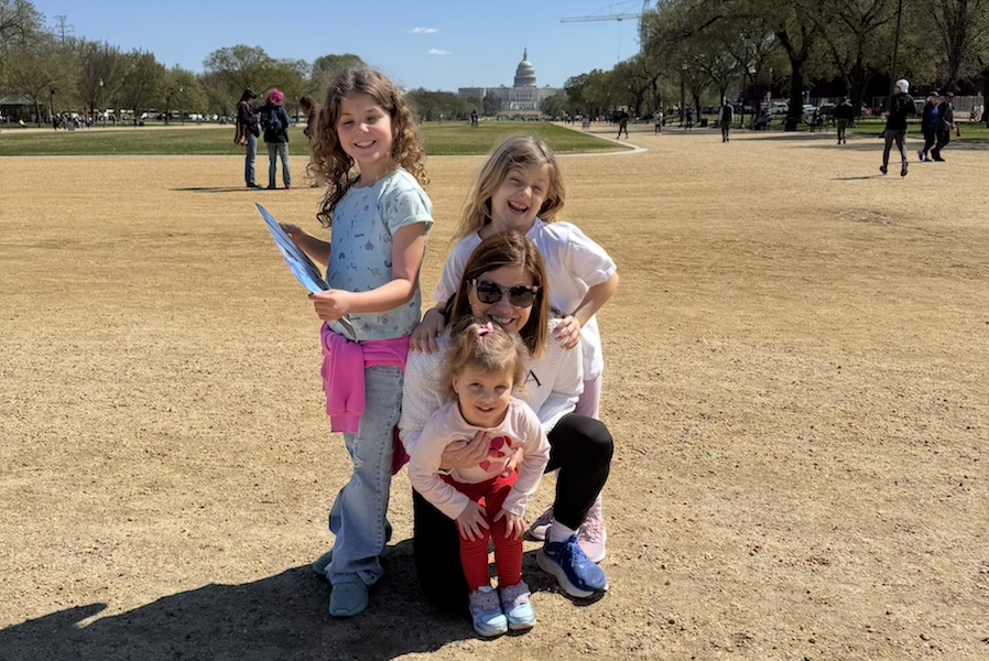 Three young kids and their grandmother pose in front of the Capitol on the National Mall. 