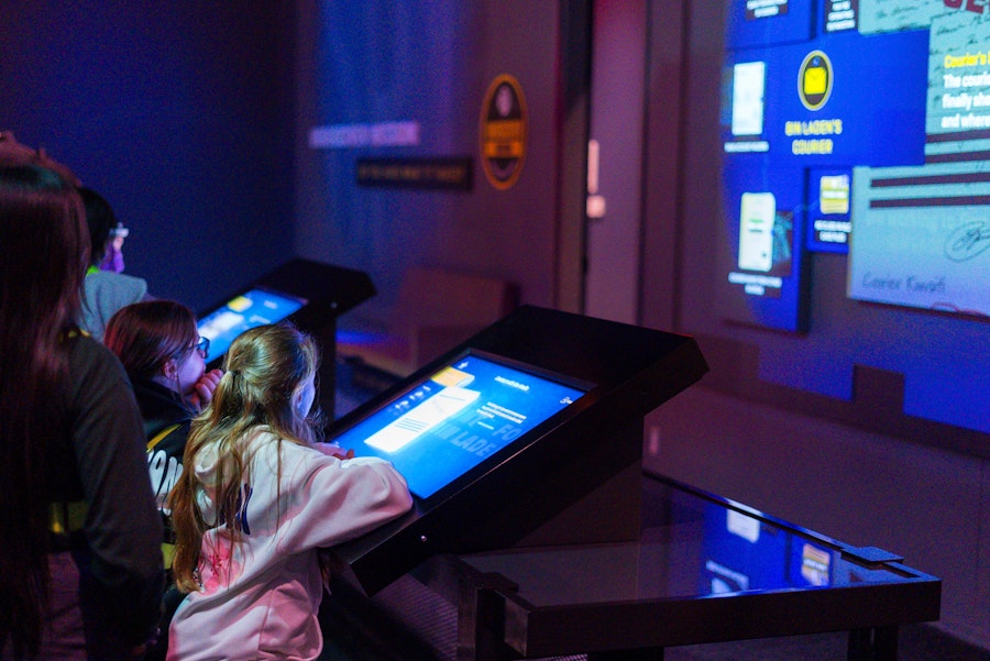 Children using touch screens in an interactive exhibit at the International Spy Museum.