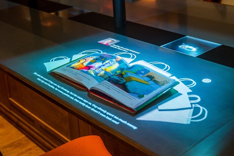 An interactive digital display at Planet Word Museum projects images and text around an open illustrated children’s book.