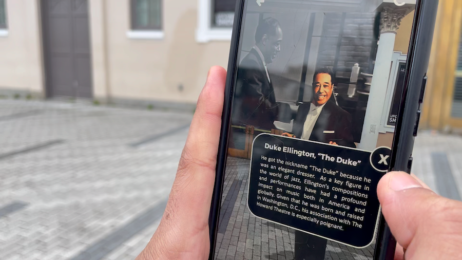 A smartphone screen displays an augmented reality portrait of Duke Ellington with historical text information.