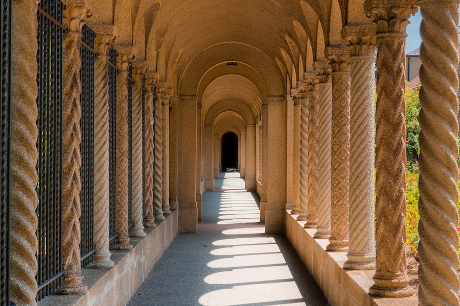 Sunlight casts repeating shadows through the arched cloister walkway at the Franciscan Monastery of the Holy Land.