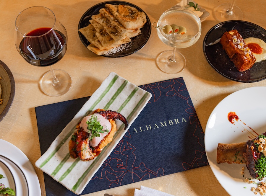 A spread of artfully plated dishes and drinks is arranged on a restaurant table.