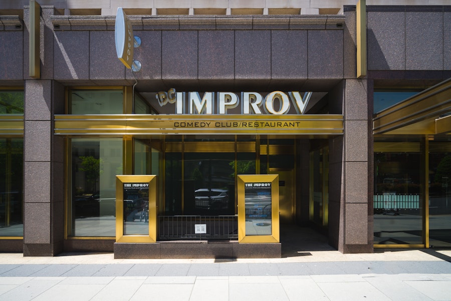 Front of Improv comedy club with two yellow-trimmed doors and large IMPROV sign