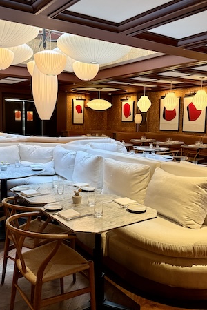 Cozy restaurant interior with cushioned seating, wooden tables, and warm pendant lights