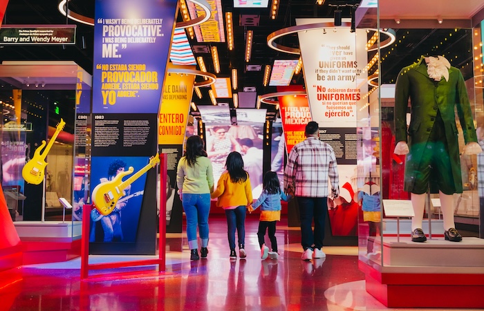 Bright, colorful shopping street at night with neon signs and pedestrians walking away