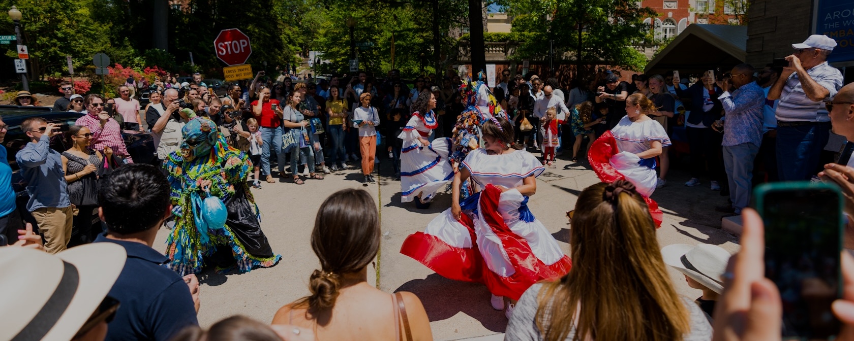 Crowd watches performers in red, white and blue costumes at an outdoor parade