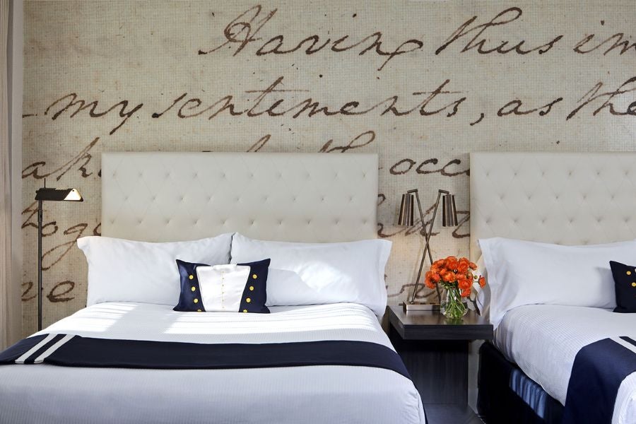 Two twin beds in a beige room, with orange flowers between them