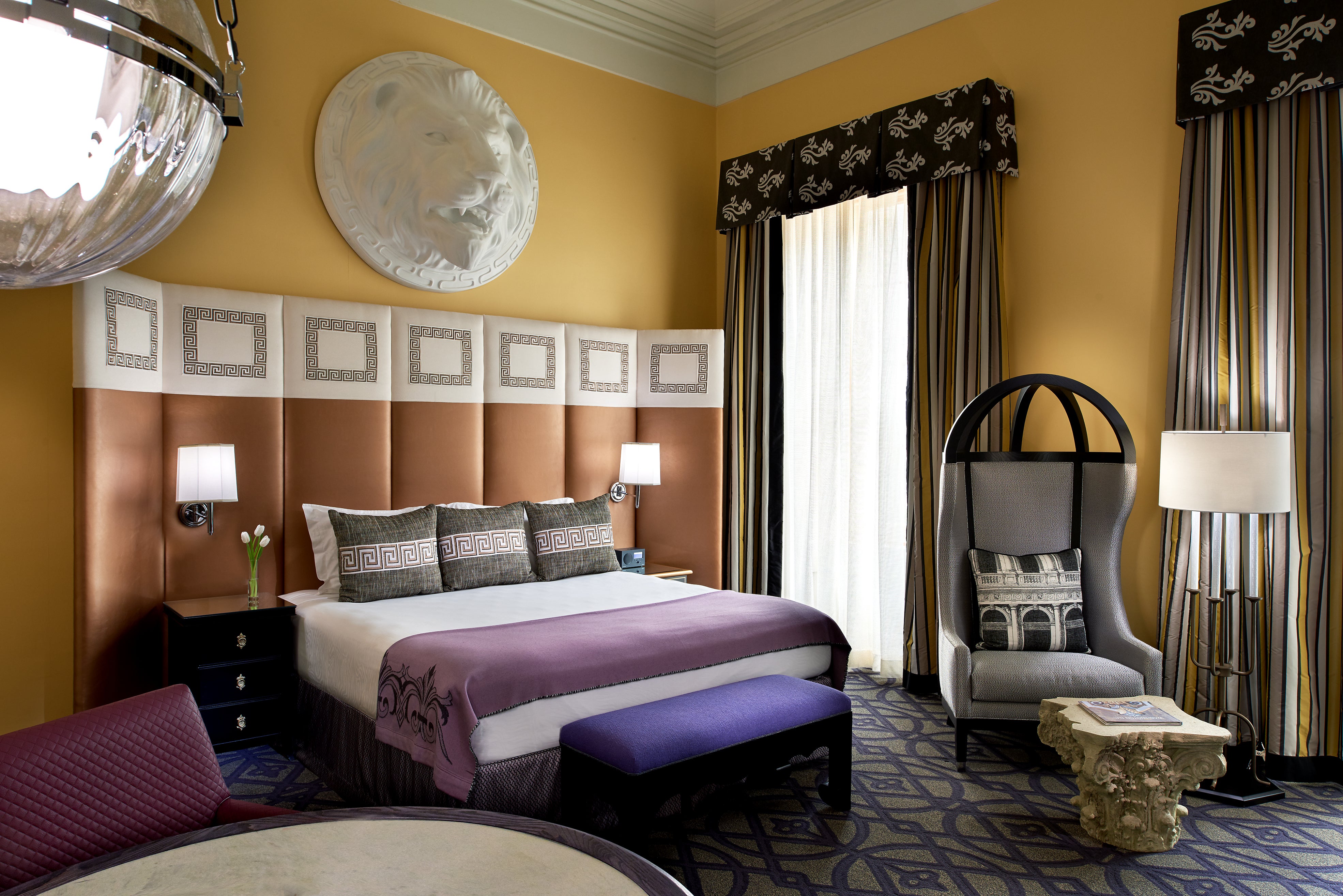 Hotel room with two beds, yellow walls, striped curtains, and a hanging chair