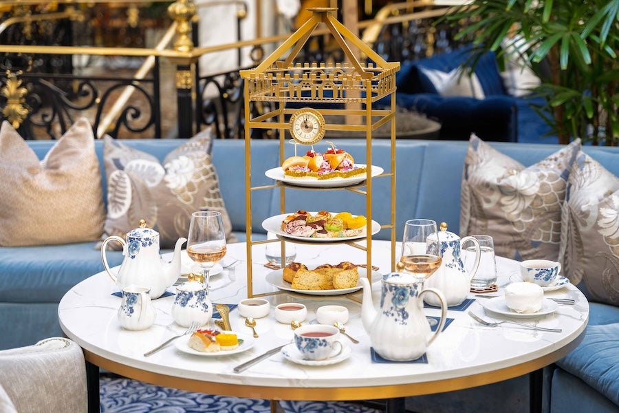 Three-tier afternoon tea stand on a table with teacups in a cozy lounge