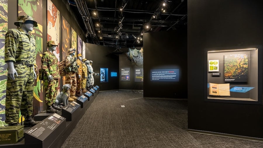 Museum hallway with military uniforms and artifacts displayed along the left wall