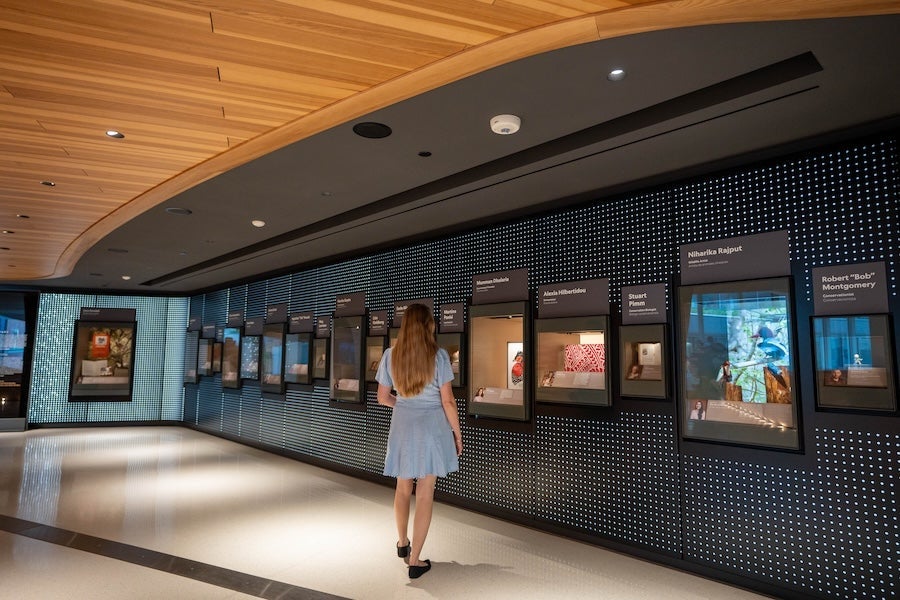 Woman in blue dress walking past framed posters in a modern gallery corridor
