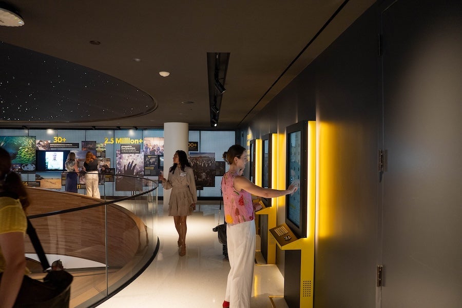 Two people walking down a modern hallway with glowing yellow wall panels