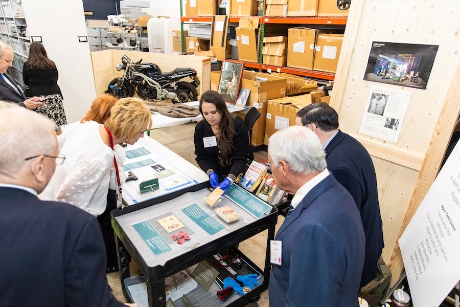 People gathered around archival items on a table in a workshop setting.