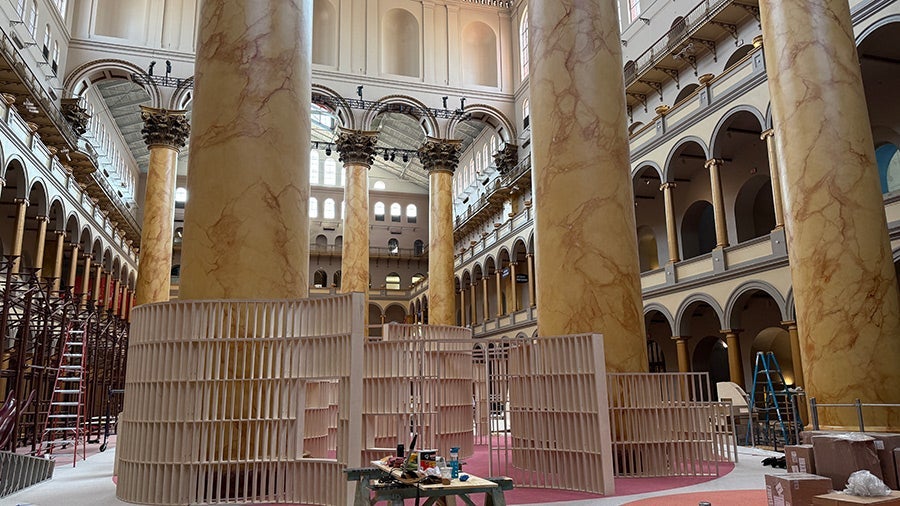 The Great Hall of the National Building Museum interior with tall columns and circular scaffolding around the Playground installation