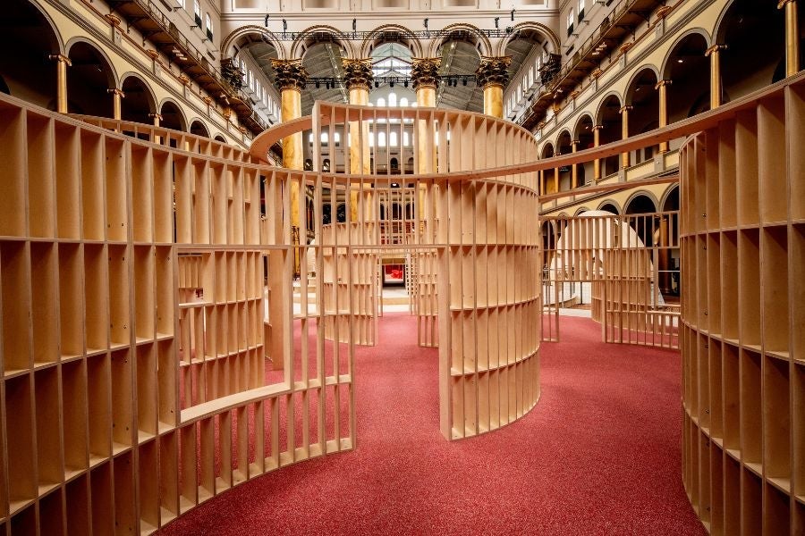 View inside the circular wooden maze at the National Building Museum’s PLAYGROUND exhibition, with curved pathways leading through the interactive installation.