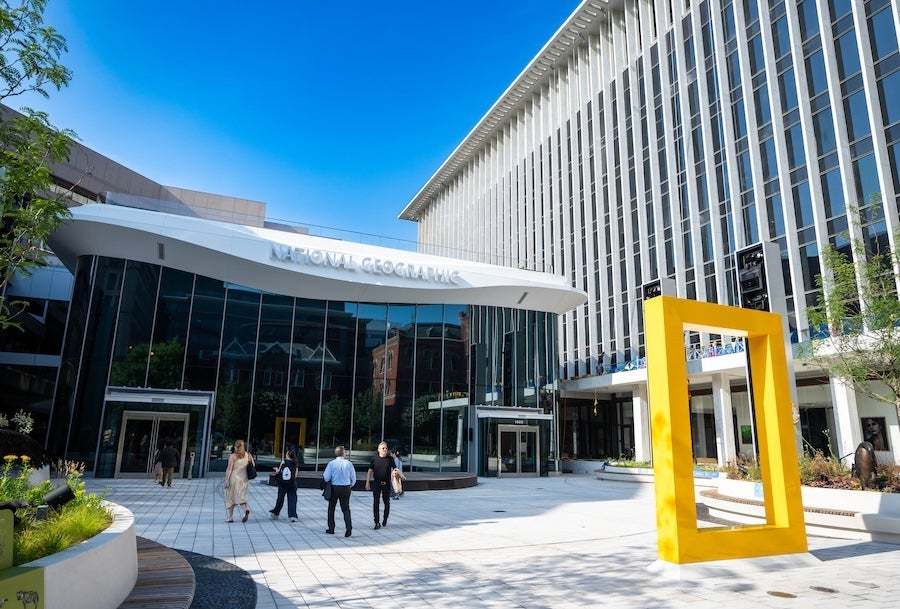 National Geographic Museum of Exploration entrance with glass facade, plaza seating and large yellow frame sculpture