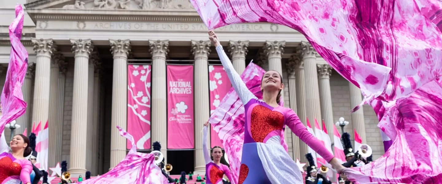 Dancers in the National Cherry Blossom Festival Parade wearing pink and red