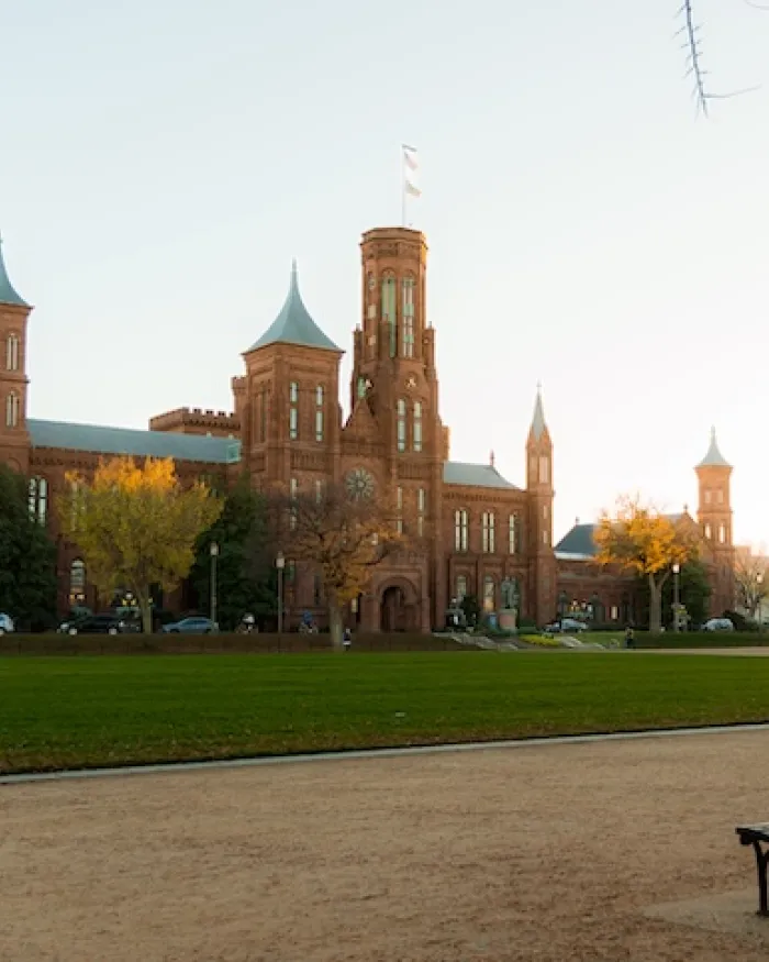 A view of the Smithsonian Castle across the National Mall in golden, summer light.