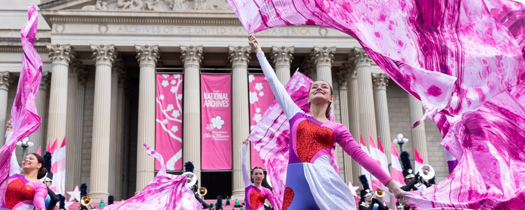 Dancers in the National Cherry Blossom Festival Parade wearing pink and red