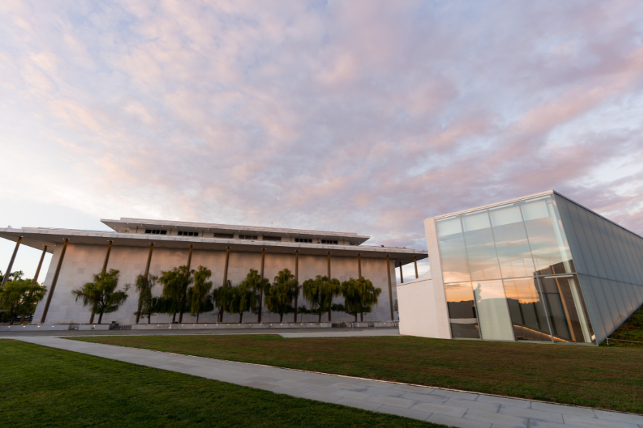 The Kennedy Center in Washington, DC, glows in the early morning light with dramatic clouds reflecting off its modern glass extension.
