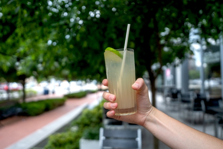 A hand holds out a refreshing green cocktail with lime.