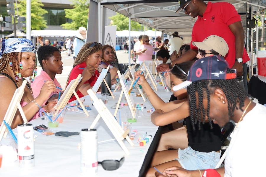 Participants concentrate on small canvas paintings during a guided outdoor workshop.