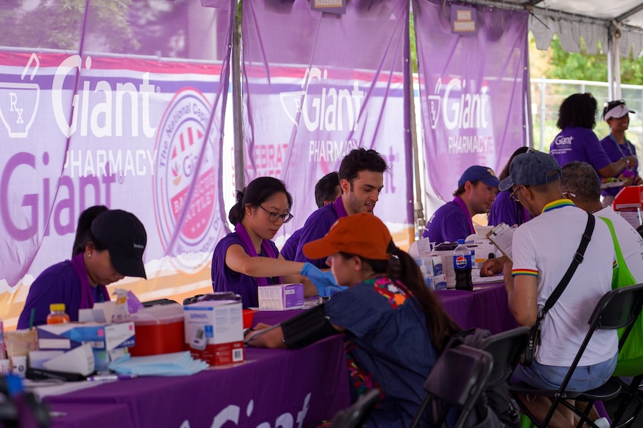 Community members receive health screenings from staff at a Giant Pharmacy tent.
