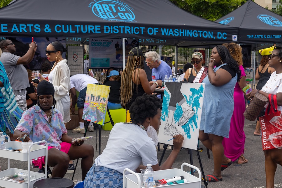 Artists and visitors gather under tents to paint and engage in creative activities.